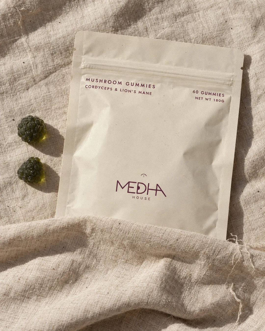The Medha House pouch resting in folds of cream linen in soft morning light